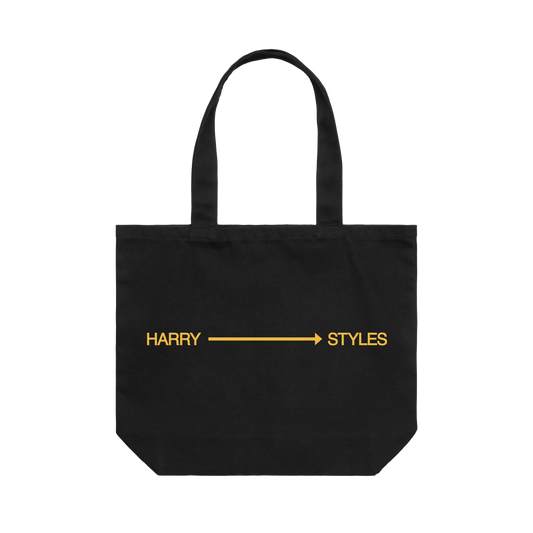 Black extra large tote bag from Harry Styles merchandise featuring yellow arrow graphic with Harry Styles text across front panel design